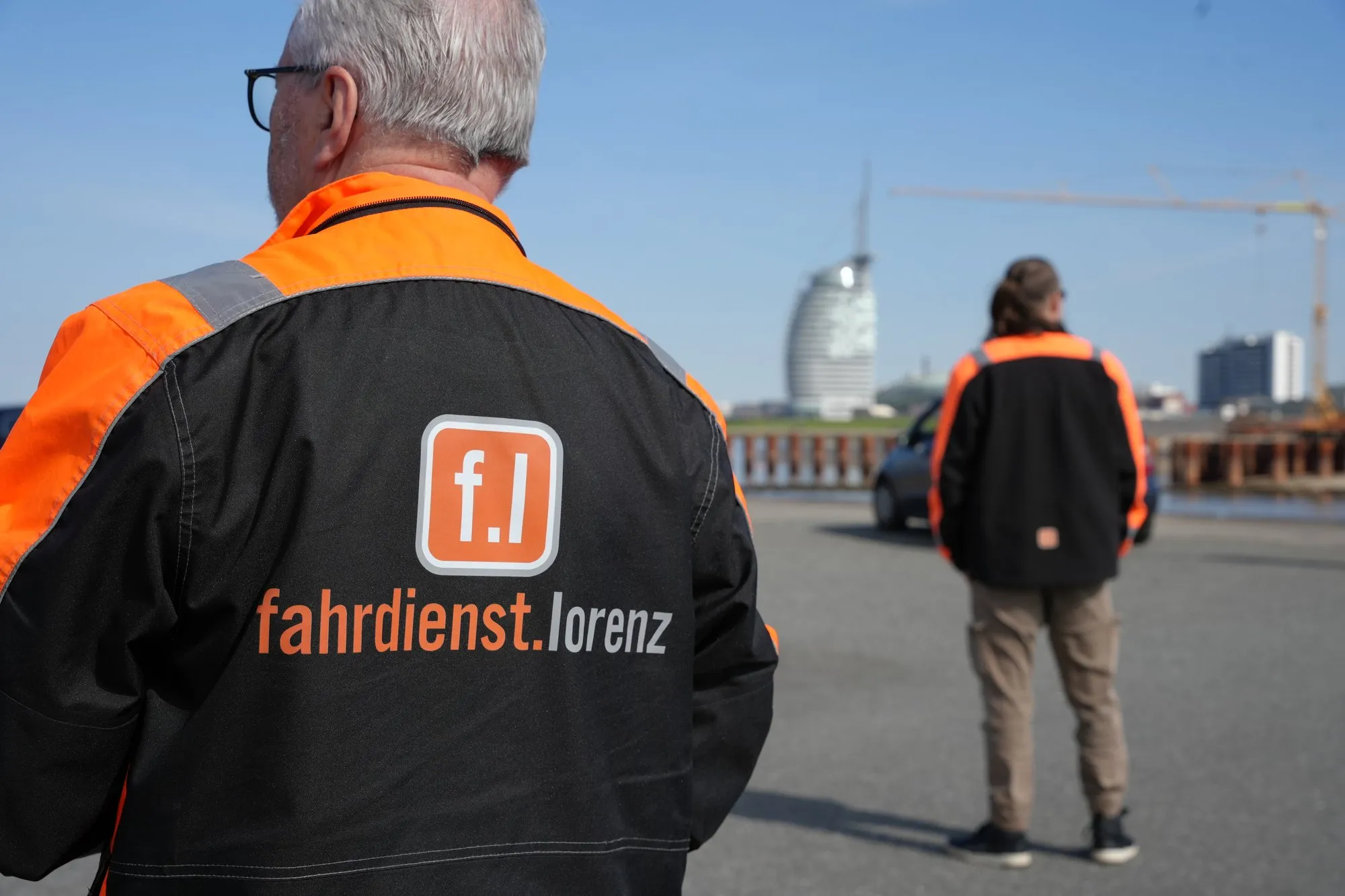 Fahrdienst Lorenz – Mitarbeiter in Firmenkleidung vor der Bremerhavener Skyline