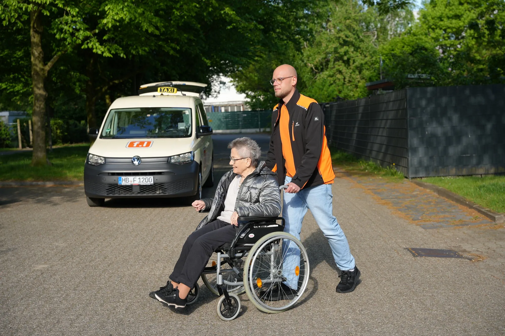Fahrdienst Lorenz – Fahrer begleitet Fahrgast im Rollstuhl zum Fahrzeug